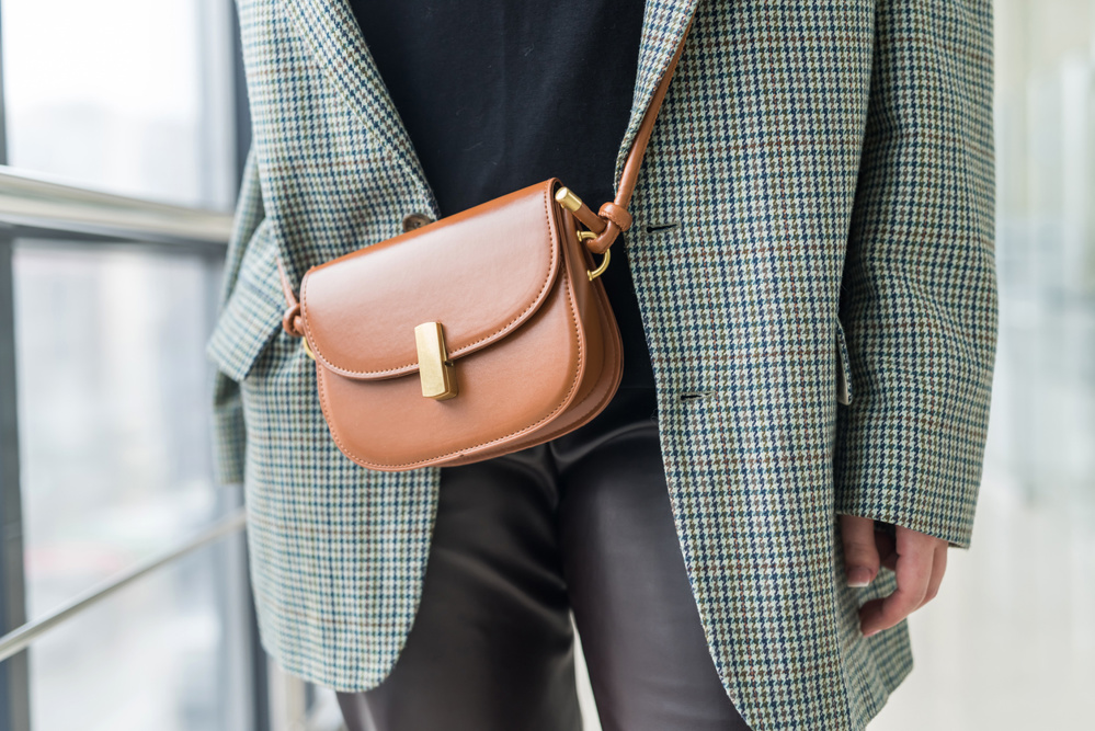 Stylish beautiful young woman in elegant clothes with a brown leather handbag on a strap. Style concept