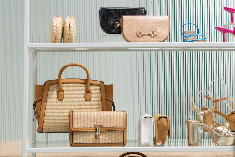 A retail display of handbags and shoes is seen with beautiful fluted glass in the background