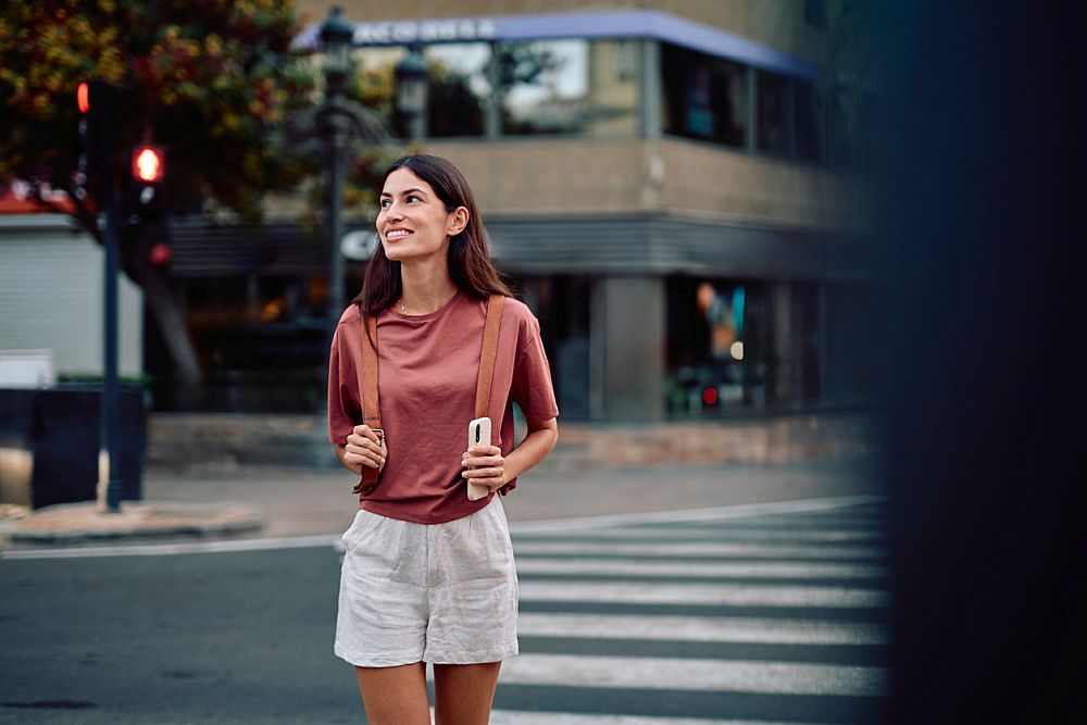  oman smiling while walking on city crosswalk